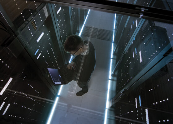 Aerial view looking down on a guy working on a laptop in a data center