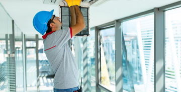 Technician working thru an open ceiling HVAC vent